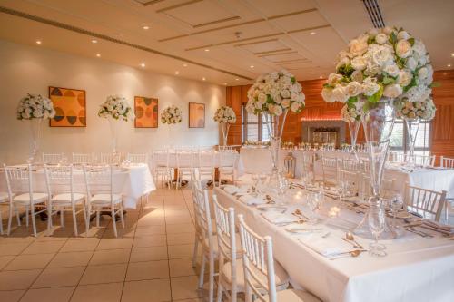 a banquet hall with white tables and chairs and flowers at Thorpe Park Hotel and Spa in Leeds