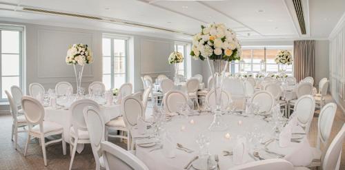 a room with a long table with white chairs and flowers at Thorpe Park Hotel and Spa in Leeds