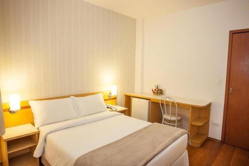 een hotelkamer met een bed en een bureau bij Hotel Arujá in Arujá
