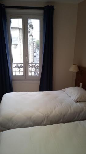 a bed in a room with a large window at Hôtel De La Perdrix Rouge in Paris