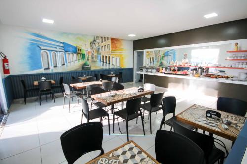 a restaurant with tables and chairs and a bar at Hotel Encantos de Penedo Alagoas in Penedo