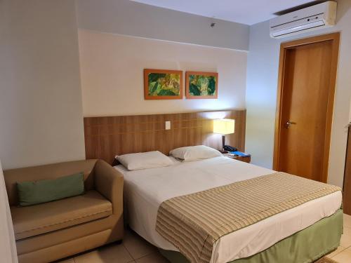 a hotel room with a bed and a chair at Flat Brasília - Setor Hoteleiro Norte in Brasilia