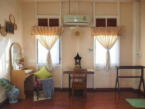 ein Wohnzimmer mit einem Tisch und 2 Fenstern in der Unterkunft KINN Stay50 Bangkok in Bangkok Yai