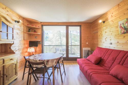 un salon avec un canapé rouge et une table dans l'établissement Residence Les Trois Soleils - maeva Home, à La Joue du Loup