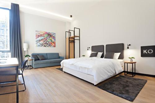 a white bedroom with a bed and a couch at Kombinat Rooms City Center in Novi Sad