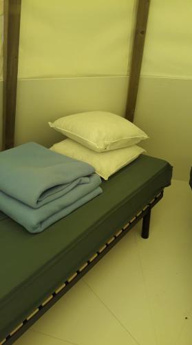 - 2 oreillers et des serviettes assises sur un lit dans l'établissement Tipi Les P'tites Maisons dans la Prairie, à Sallertaine