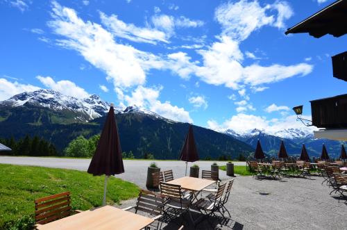 Un patio con mesas y sillas con montañas al fondo. en Panoramagasthof Kristberg, en Silbertal