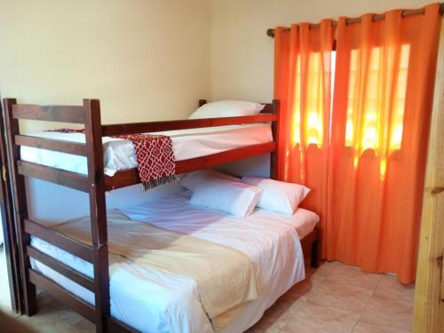 2 stapelbedden in een kamer met een oranje gordijn bij Sparkle Guest House - Self-Catering, Pool, Garden in Maputo