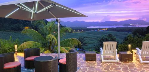 a patio with chairs and an umbrella and a view at Résidence BelKay - Sur La Baie in Ducos