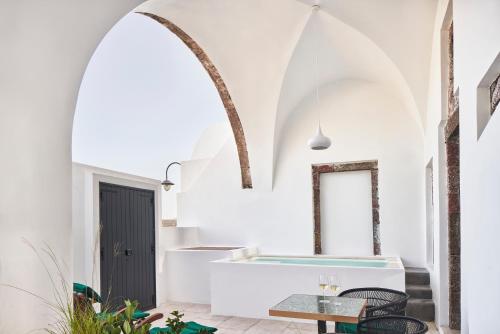 a room with a bathtub and a table at Katikies Garden Santorini - The Leading Hotels Of The World in Fira