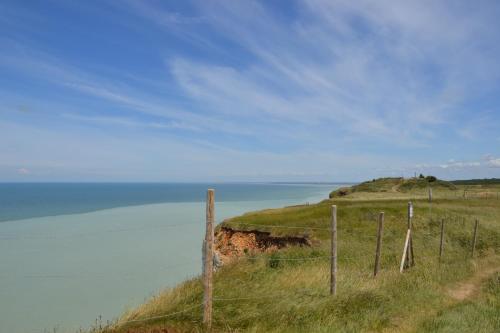 a fence on top of a grassy hill next to the ocean at B&B HOTEL Le Tréport Friville in Friville-Escarbotin