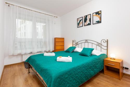 a bedroom with a green bed with two towels on it at Mokotow Business Center Apartments by Renters in Warsaw