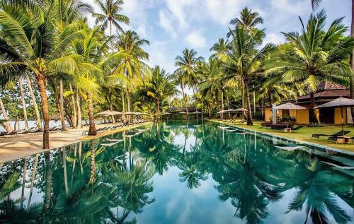 a swimming pool with palm trees and blue water at Blue Heaven Bay Beach Room in Ko Chang