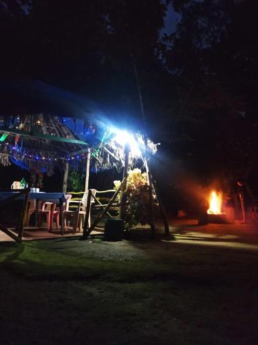a tent with a table and a fire at night at dreams home estate stay 2 in Suntikoppa
