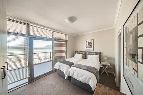 ein Schlafzimmer mit einem Bett und einem großen Fenster in der Unterkunft Surferscorner Self Catering Apartments in Muizenberg
