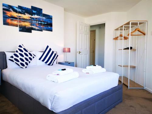 a bedroom with a large white bed with towels on it at Marina living with parking, balcony, quiet and secure in Brighton & Hove