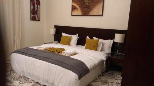a bedroom with a large bed with white sheets and yellow pillows at رميس البخاري in Buraydah