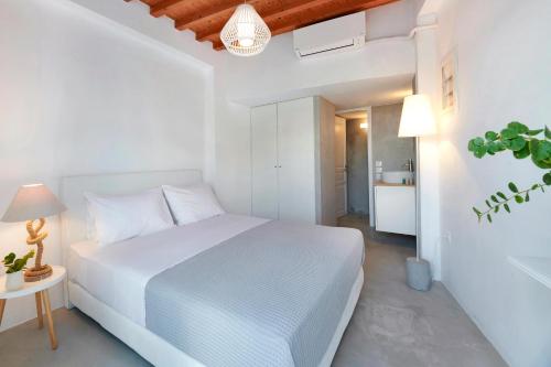Dormitorio blanco con cama blanca y mesa en The Elephant Beach House, en Kimolos