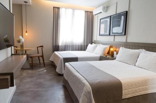 a hotel room with two beds and a table at Ritz Leblon in Rio de Janeiro