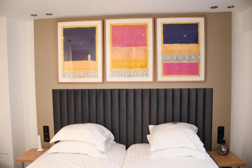 a bedroom with two beds and three paintings on the wall at Hotel Aida Opera in Paris