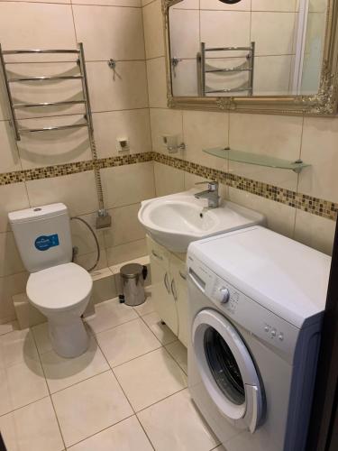 a bathroom with a toilet a sink and a washing machine at Apartment Elegant in Kyiv