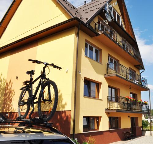 a bike on the roof of a car in front of a building at Pokoje Gościnne UAnny in Nowy Targ