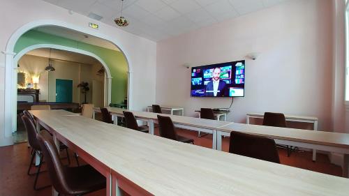 a room with tables and chairs and a tv on the wall at Hôtel Le Victoria in Draguignan