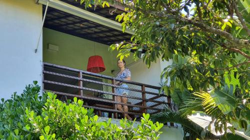 a woman standing on a balcony of a house with a red lamp at Apartment Delírios in Imbassai