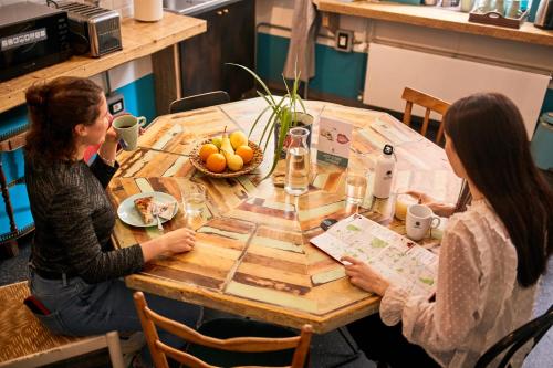 two women sitting at a table with a bowl of fruit at Madama Hostel & Bistrot in Milan