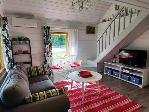 ein Wohnzimmer mit einem Sofa und einem TV in der Unterkunft Villa Kotiranta in Jämsä