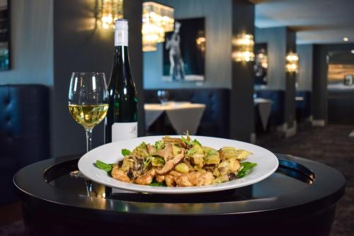 a plate of food on a table with a glass of wine at Hotel Legends in Biloxi