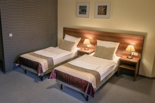 une chambre d'hôtel avec 2 lits et 2 lampes dans l'établissement Zajazd u Dziadka, à Carolinensiel