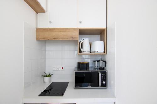 a kitchen with white cabinets and a black microwave at Phaedrus Living Seaview Studio Suite Lighthouse 52 in Paphos City