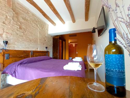 a bottle of wine sitting on a wooden table with a wine glass at Hotel Restaurant Lotus Priorat in Falset