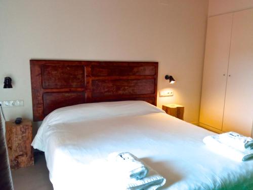 a bedroom with a large white bed with a wooden headboard at Hotel Restaurant Lotus Priorat in Falset