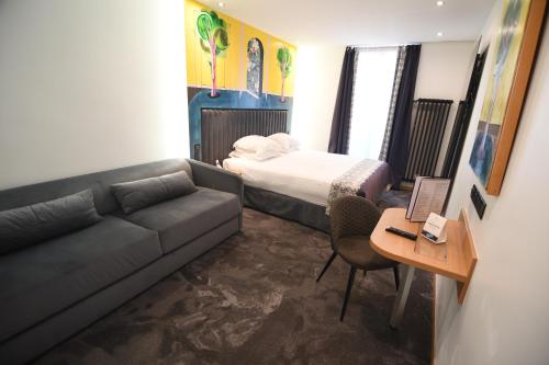 a room with a couch and a bed and a desk at Hotel Aida Opera in Paris