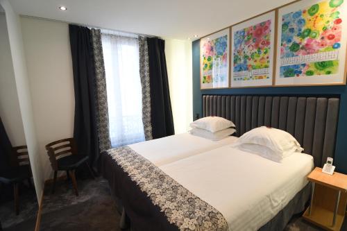 a hotel room with a bed, desk, and a painting on the wall at Hotel Aida Opera in Paris