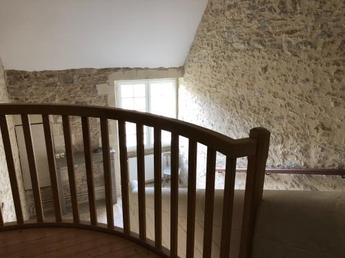 escalera de madera en una habitación con pared de piedra en Château de la Garnison en Orvault