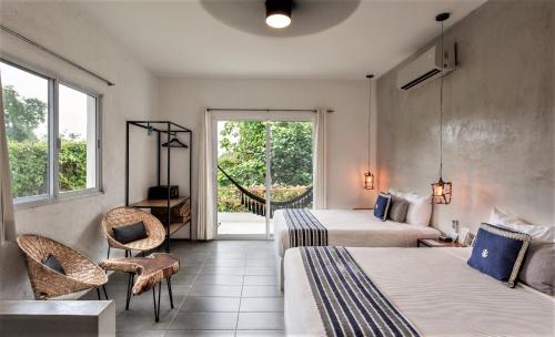 a hotel room with two beds and a balcony at Hotel Aires Bacalar in Bacalar