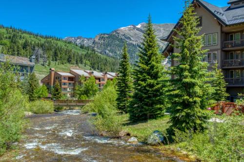 a river in front of a resort with trees at Peregrine in Copper Mountain