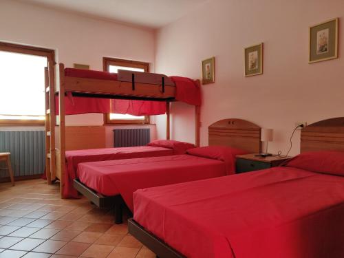 Cette chambre comprend 4 lits avec des draps rouges. dans l'établissement Ostello Europa, à San Vito al Tagliamento