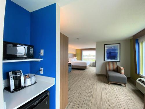 a hotel room with a bed and a room with a microwave at Holiday Inn Express Hotel & Suites Somerset Central by IHG in Somerset