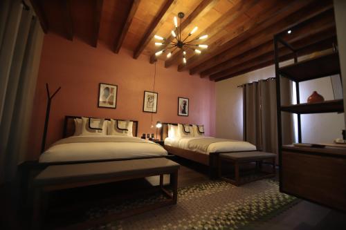a bedroom with two beds and a chandelier at Antigua Trece Hotel Fusión in Guanajuato