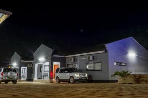 two cars parked in front of a building at night at Greyville Apartments in Lusaka