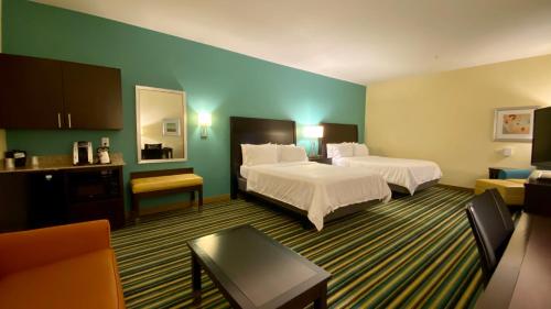 a hotel room with two beds and a couch at Holiday Inn Express Hotel & Suites Orlando East-UCF Area by IHG in Orlando