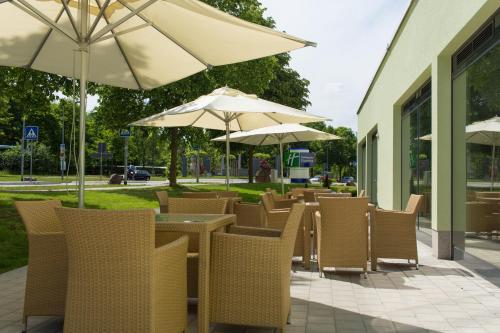 a row of tables and chairs with umbrellas at Holiday Inn Express Neunkirchen by IHG in Neunkirchen