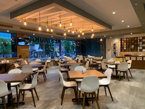 a restaurant with wooden tables and white chairs at Holiday Inn Express - Mexico Basilica, an IHG Hotel in Mexico City