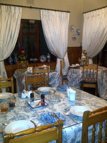 a dining room with a table with plates and chairs at Mulligans Guest Lodge in Hermanus