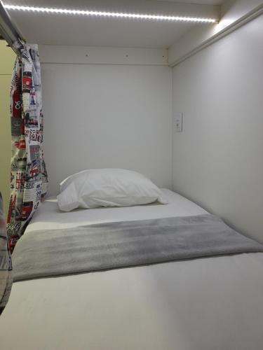 a bed in a room with a white wall at Casa de Oliveira Hostel in Torres