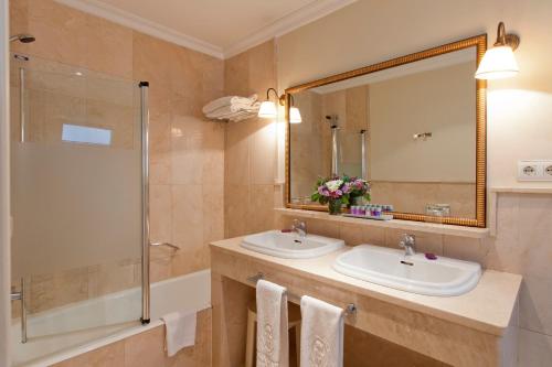 a bathroom with two sinks and a shower and a mirror at Hotel Doña María in Seville